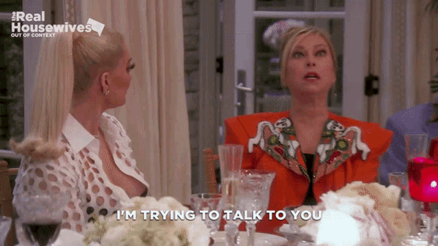two women sitting at a table with the words i 'm trying to talk to you on the screen