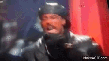 a man in a helmet is standing in front of a red curtain and screaming .