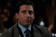 a man in a suit and tie is holding a glass of whiskey in his hand .
