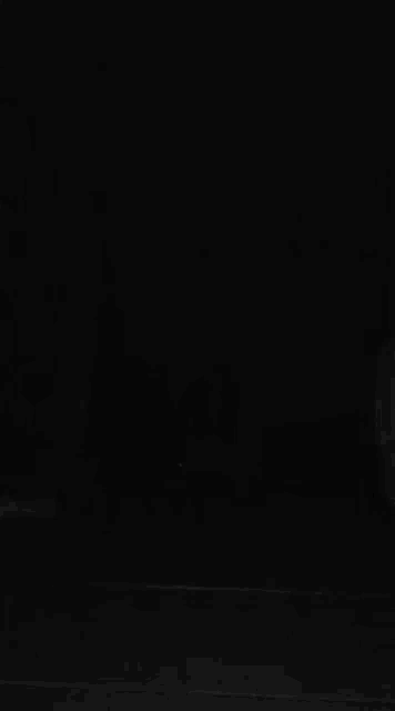 a black and white photo of a person sitting on a table in the dark .