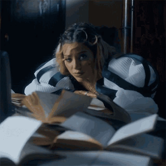 a woman is sitting at a table with a bunch of books on it