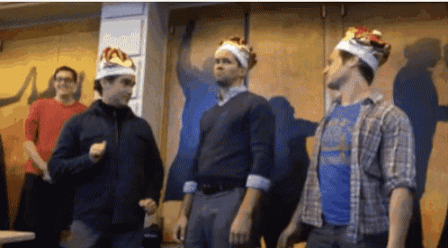 three men wearing burger king crowns are dancing in a room .