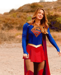 a woman in a superman costume is standing in the dirt .