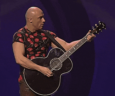 a bald man in a cherry shirt is holding a black guitar