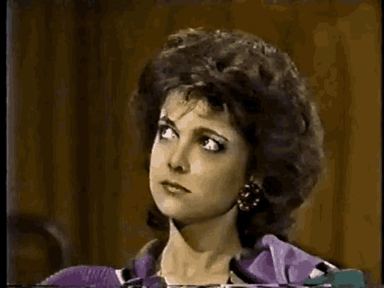 a close up of a woman 's face with a purple shirt
