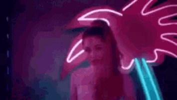 a woman is standing in front of a neon sign in a room .