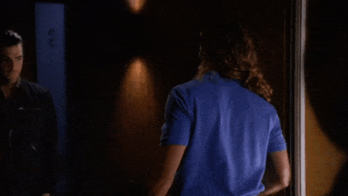 a woman in a blue shirt is standing in front of a man in a black shirt .
