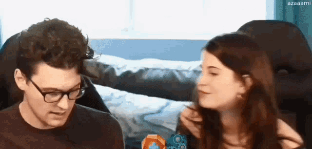 a man and a woman are sitting next to each other and the woman is looking at the man