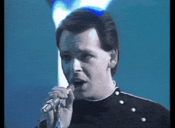 a man is singing into a microphone on stage .