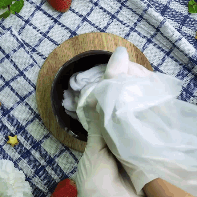 a person wearing gloves is holding a plastic bag over a bowl