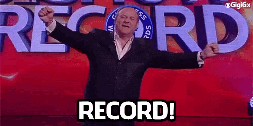 a man in a suit stands in front of a sign that says record