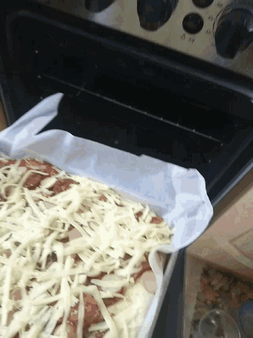 a casserole dish filled with meat and cheese is sitting on top of a stove