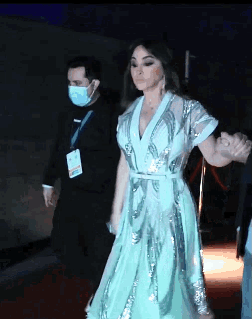 a woman in a green dress is walking down a red carpet