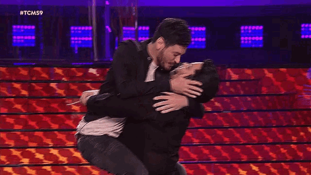 two men are hugging each other on a stage while laughing .