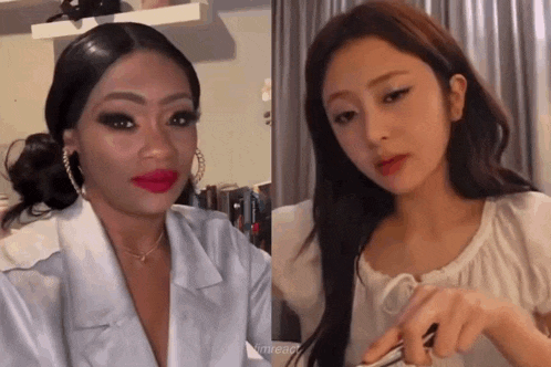 two women are standing next to each other in a room . one of the women is wearing red lipstick .