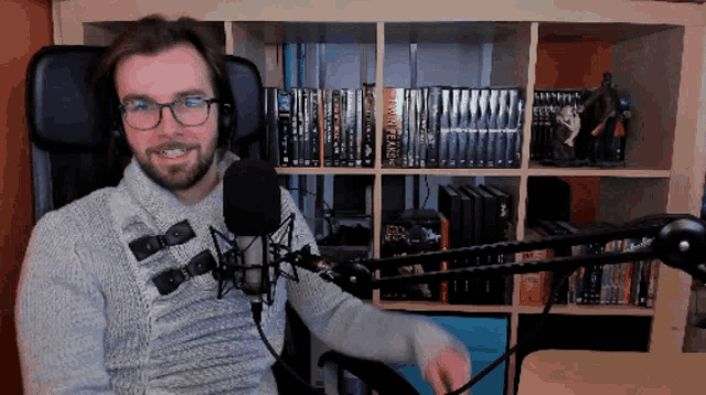 a man sitting in front of a microphone with a shelf full of star wars books