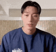 a young man in a blue shirt is looking at the camera .