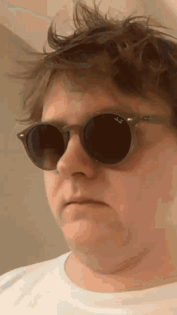 a man wearing sunglasses and a white shirt is making a face