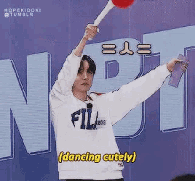 a man in a white sweatshirt is holding a lollipop in his hand and dancing cutely .