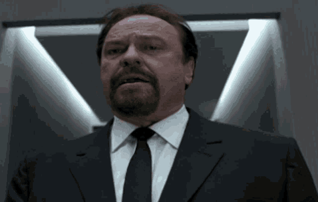 a man in a suit and tie is standing in front of a door
