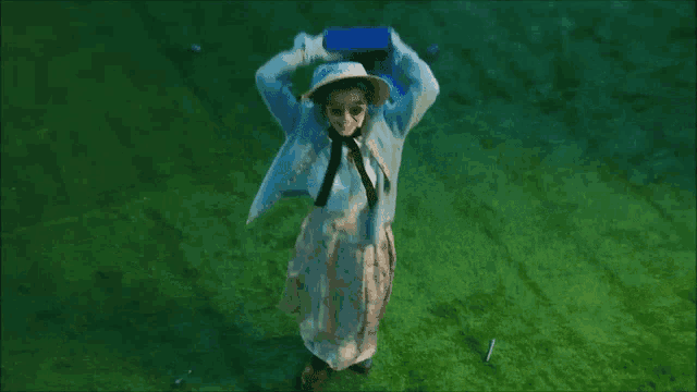 a woman in a white hat is dancing on a green grass field .