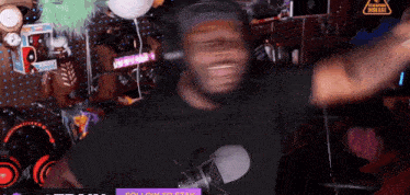 a man wearing headphones and a black shirt is dancing in front of a sign that says streaming disgrace ..
