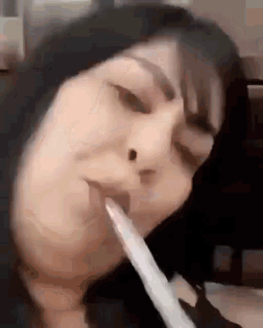 a close up of a woman smoking a cigarette with her mouth open .