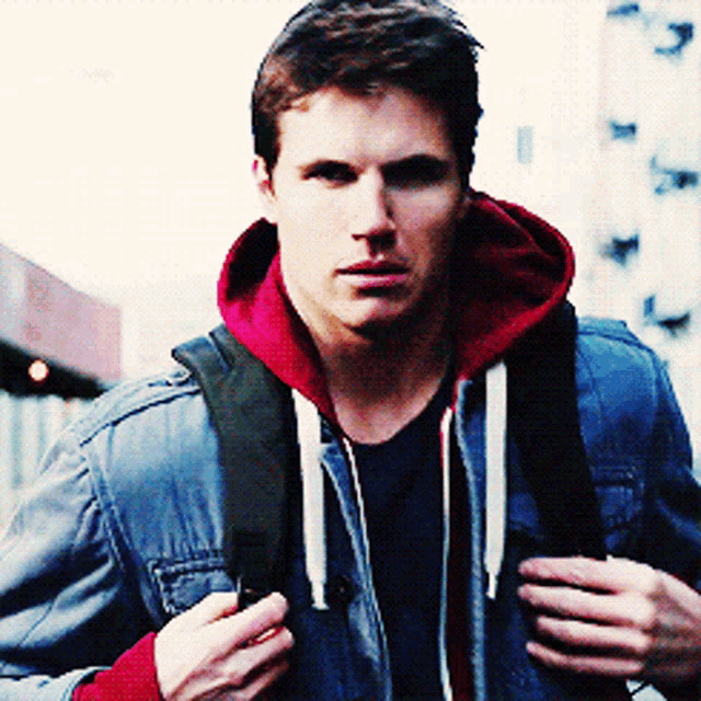 a young man wearing a denim jacket and a red hoodie