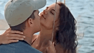 a man and a woman are kissing on a boat .