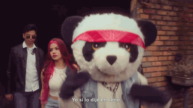 a man and a woman standing next to a stuffed panda bear with the words yo si lo dije en serio below it