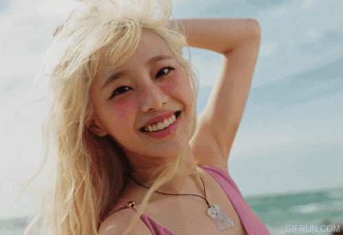 a woman in a pink bikini is smiling with gifrun.com in the lower right corner