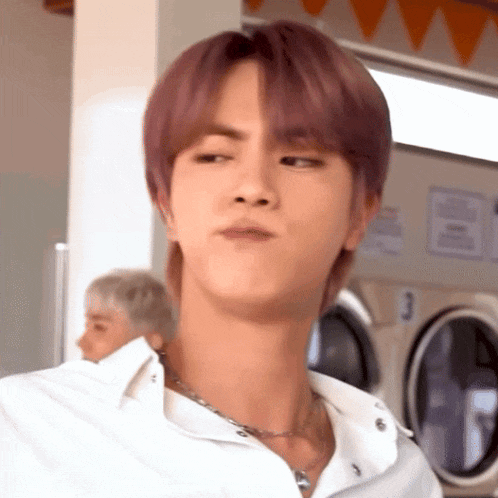 a man with purple hair is standing in front of a laundromat .