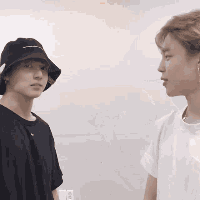 two men standing next to each other one wearing a bucket hat