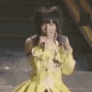 a woman in a yellow dress is dancing on a stage .
