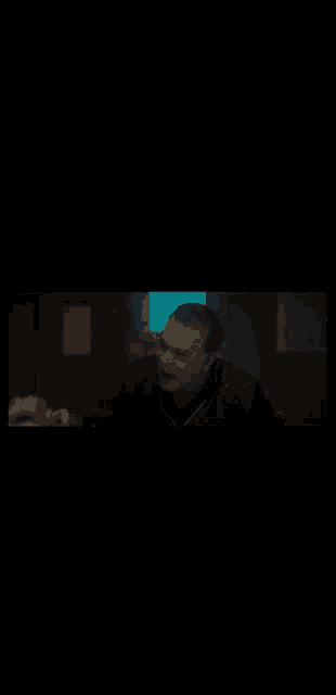 a man is sitting at a table in a dark room talking