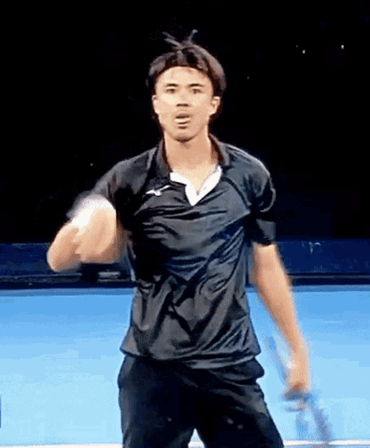 a man in a black shirt is holding a tennis racquet on a blue court .
