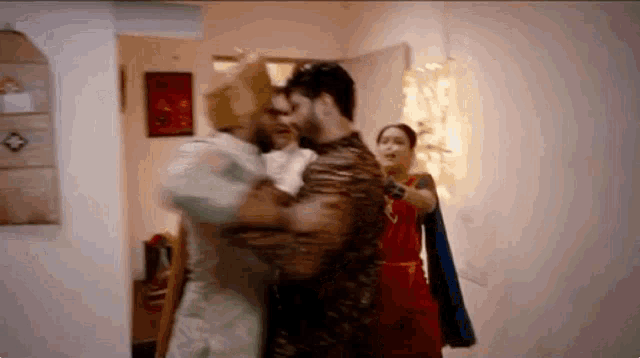 a man is holding another man in his arms in a room .