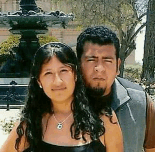 a man and a woman posing for a picture in front of a fountain .
