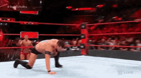 two men are wrestling in a wrestling ring and one of them is kneeling down .