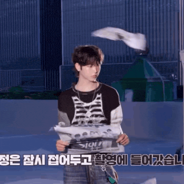 a young man is holding a newspaper with foreign writing on it ..