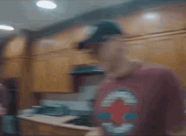 a man wearing a red converse shirt is standing in a kitchen