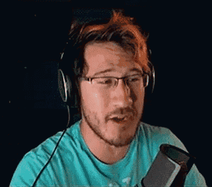 a man with glasses and headphones is sitting in front of a microphone .
