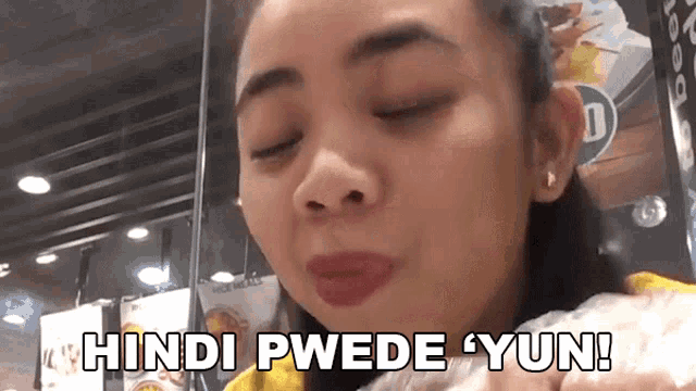 a woman in a yellow shirt is eating a sandwich and says hindi pwede yun