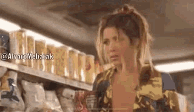 a woman is standing in a grocery store next to a shelf of chips .
