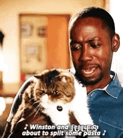 a man is holding a cat in his arms and singing .