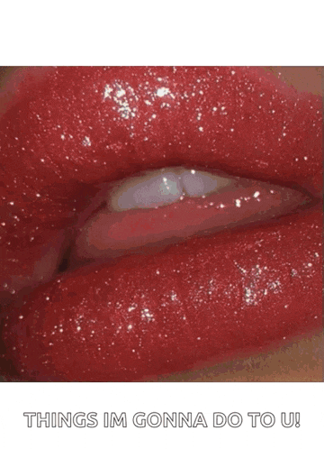 a close up of a woman 's red lips sticking out her tongue .