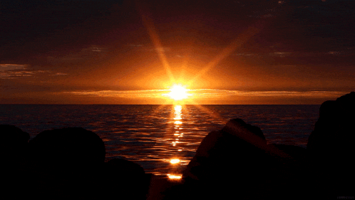 a sunset over a body of water with the sun shining brightly