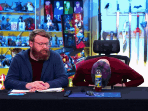 a man sitting at a table with his head on his knees and a bottle of dr pepper in front of him