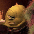 mike wazowski from monsters inc is sitting at a desk with a book .