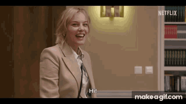 a woman in a suit and tie is laughing and says hi .